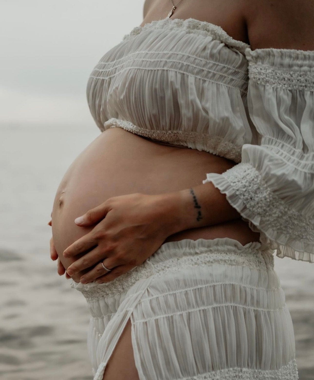 A pregnant lady stands holding her bump wearing Everything Lace Hire Anabelle Two Piece Maternity Photoshoot Set