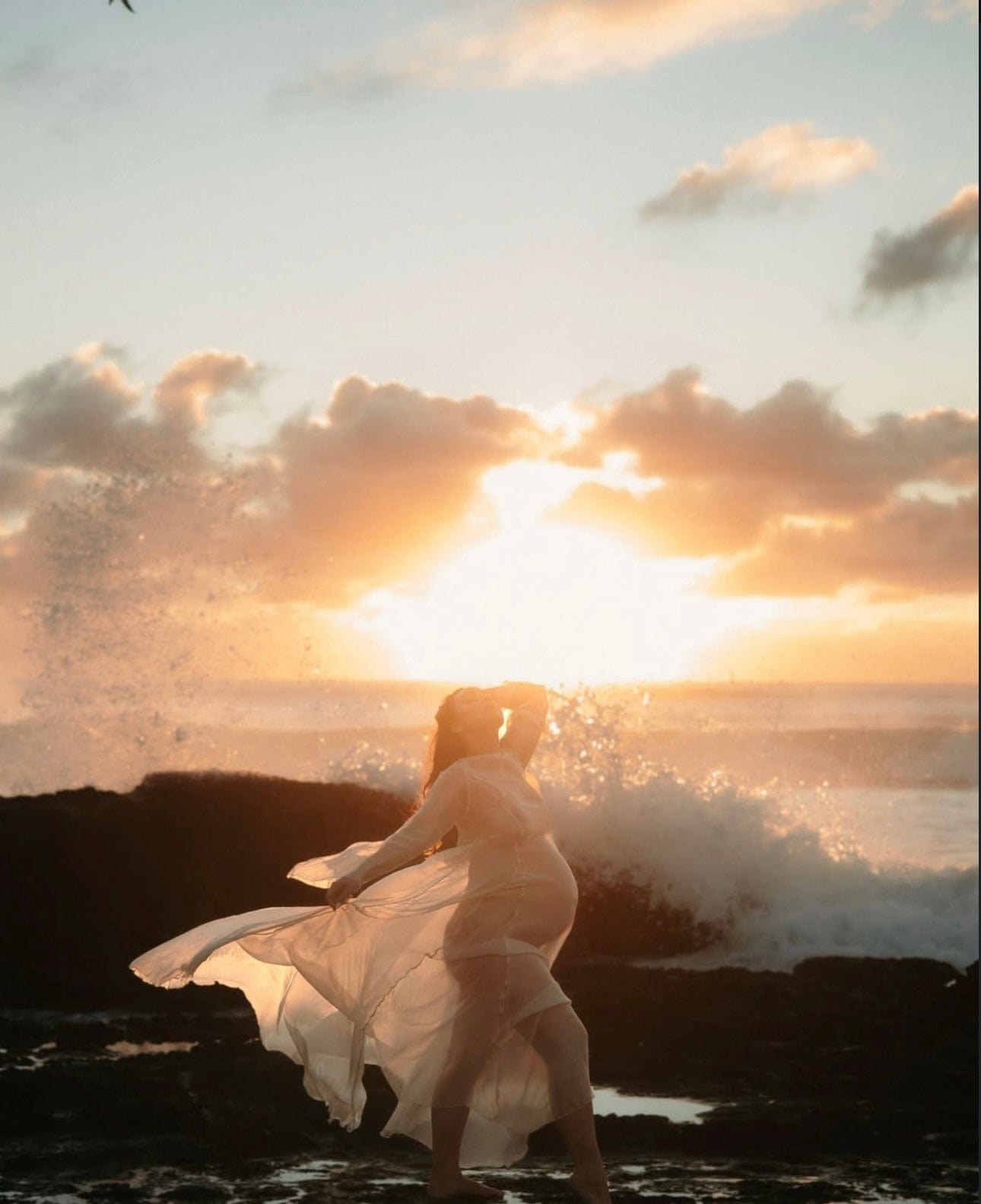 Mother standing on rocks at the beach showcasing her pregnancy wearing Everything Lace Hire Vienna Dress