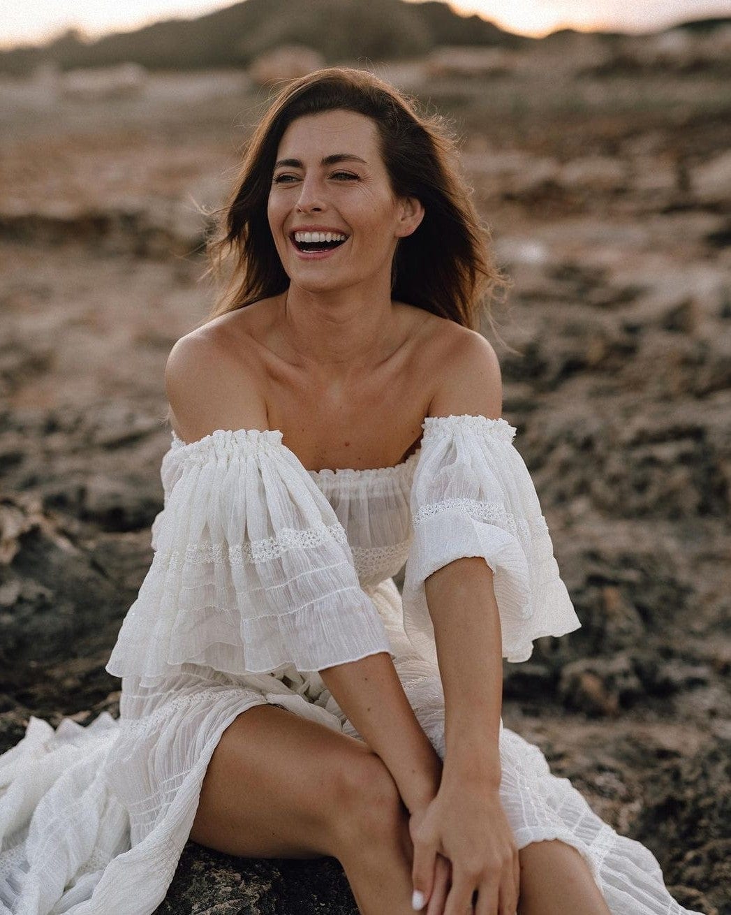 A beautiful non-pregnant mother sits on the rocks watching her children during a family photoshoot wearing Everything Lace Hire's Anabelle Two Piece Set.