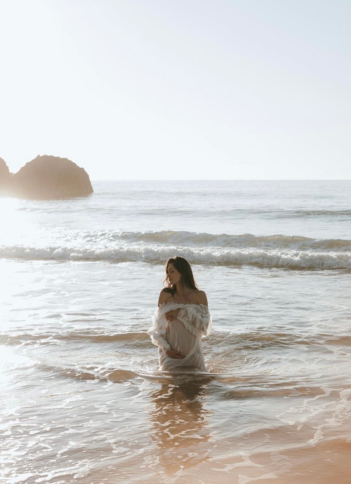 Mum to be kneeling down in the sea at sunrise wearing Everything Lace Hire Camille Maternity Photoshoot Dress