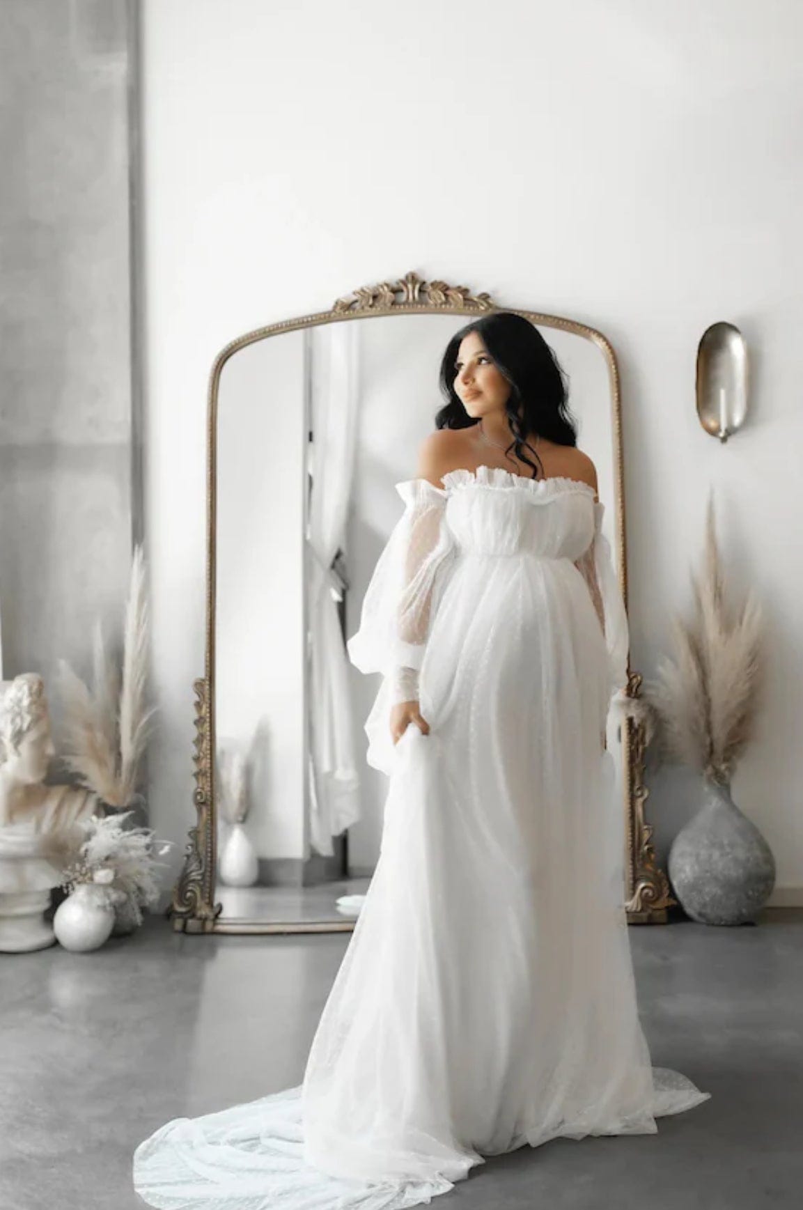 A pregnant lady stands in front of a large mirror during her studio maternity photoshoot wearing Everything Lace Hire Grace Dotted Tulle Maternity Dress