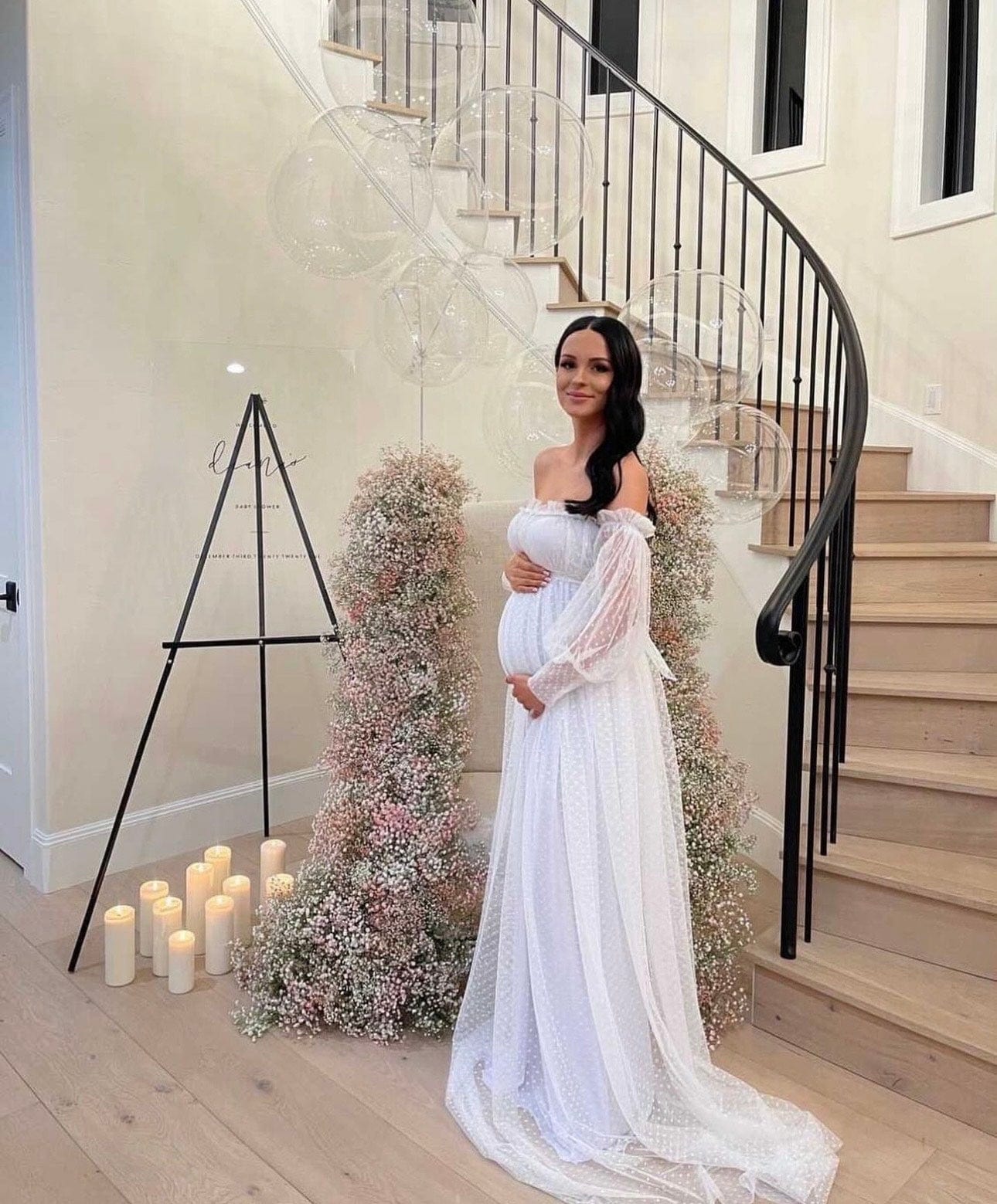 A pregnant lady stands at the bottom of the stairs at her baby shower wearing Everything Lace Hire Grace Dress