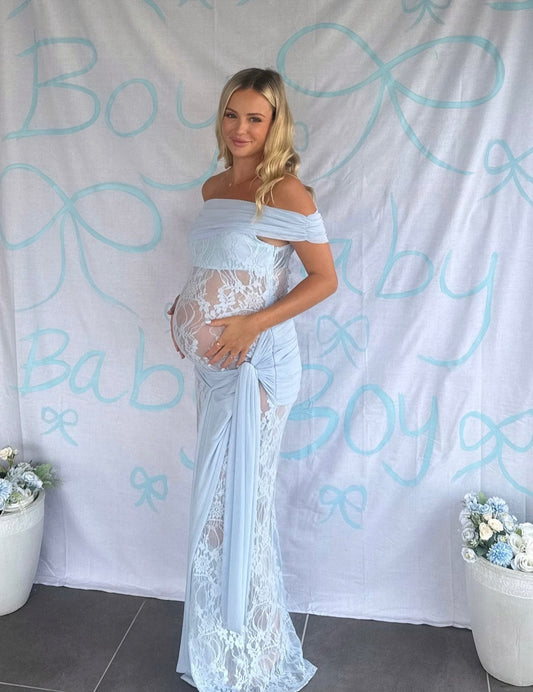 Pregnant woman wearing Everything Lace Hire Gracie Twist a lace maternity Baby Shower dress standing in front of a Baby Boy Sign backdrop.