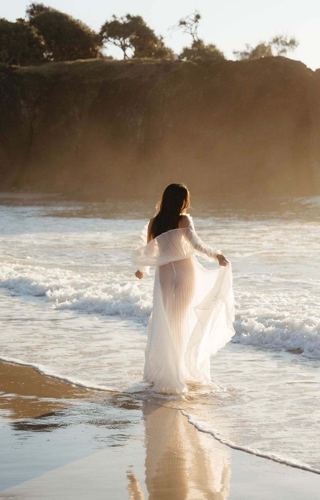 Beach photoshoot walking in the sea at sunset wearing Everything Lace Hire Camille Photoshoot Dress