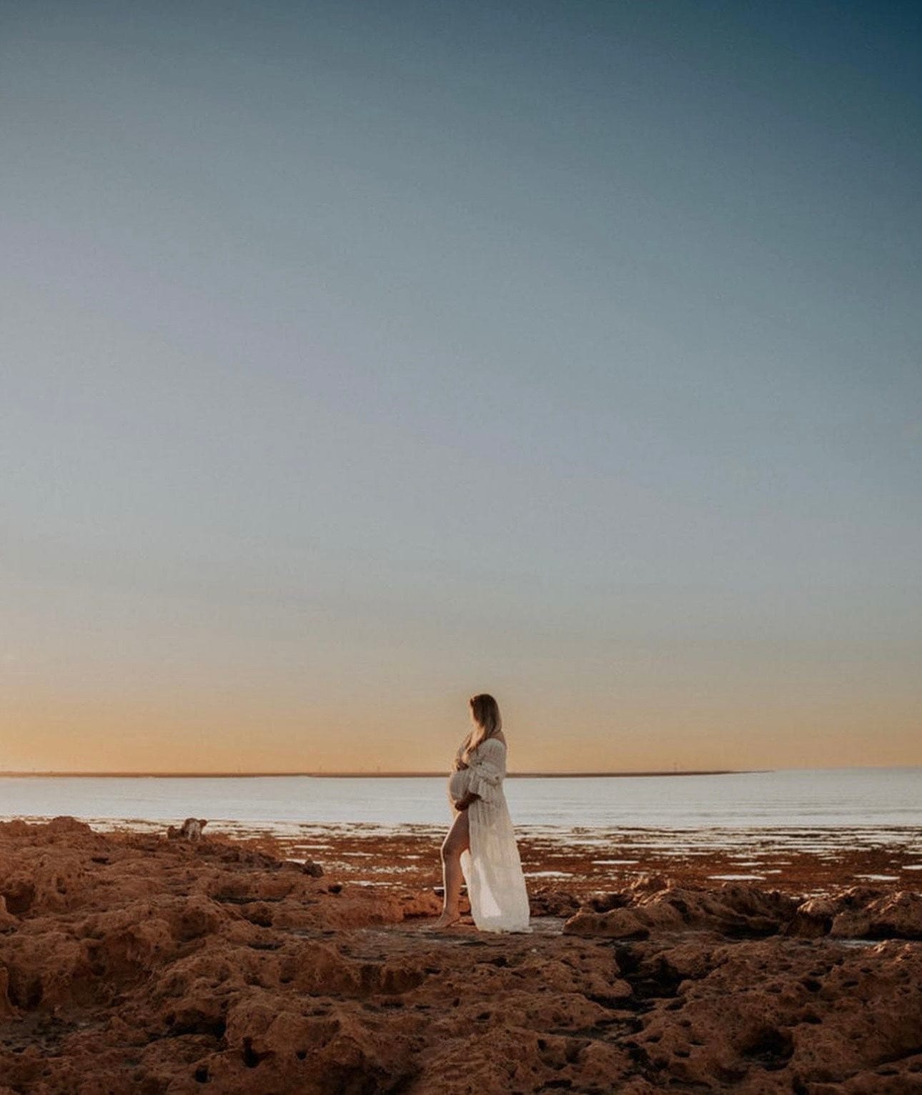 Beach photoshoot on the rocks at Sydney beaches wearing Everything Lace Hire Anabelle Photoshoot Dress which is a soft chiffon Ivory dress with puff sleeves