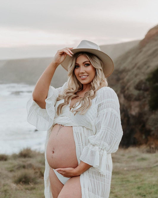 A stunning pregnant lady wearing Everything Lace Hire's Anabelle Dress during her cliff side maternity photoshoot.