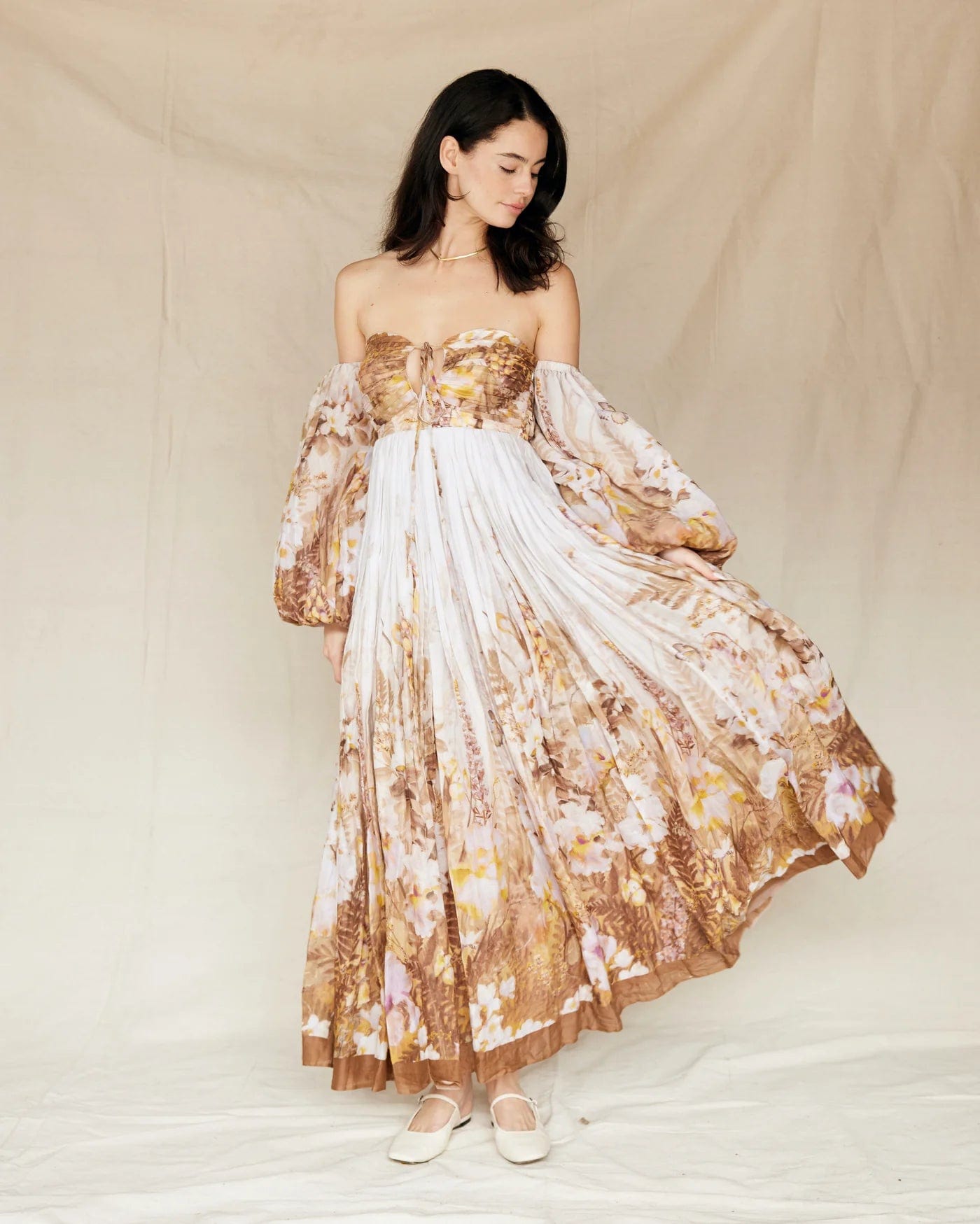 A lady standing in a studio wearing Everything Lace Hire Rooh Bronte Botanica Dress a brown floral dress