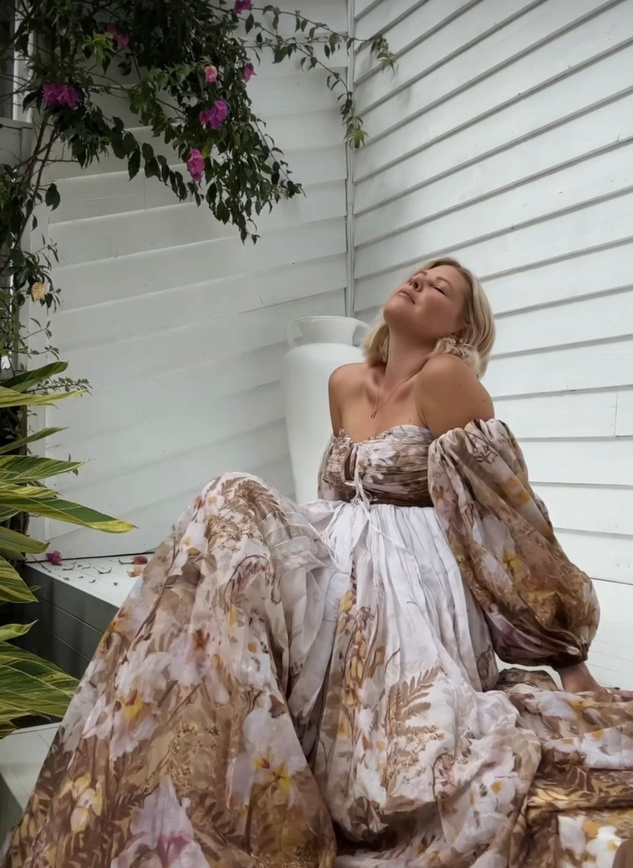 A lady sitting on the step looking up wearing Everything Lace Hire Rooh Collective Bronte Botanica Dress