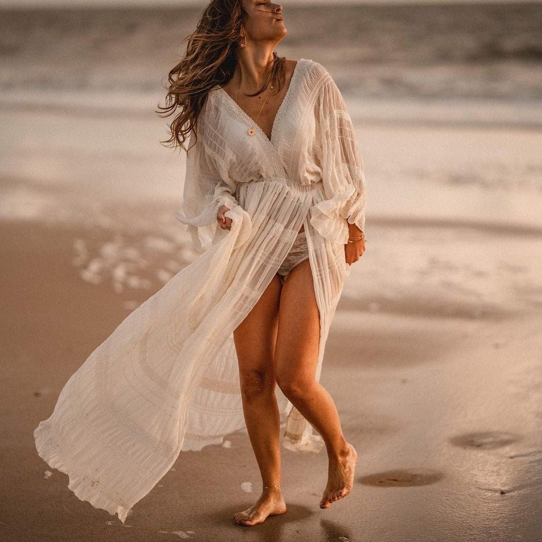 A stunning mum during a photoshoot on the beach wearing a cream chiffon dress. This photoshoot dress is available to hire.
