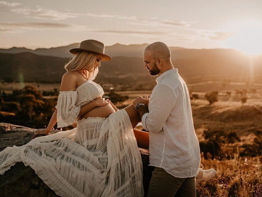 A mother sits on a cliff edge during her maternity photoshoot wearing Everything Lace Hire's Anabelle Two Piece Set showing her bump.